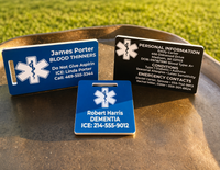Three medical alert tags on a metal surface with grass in the background