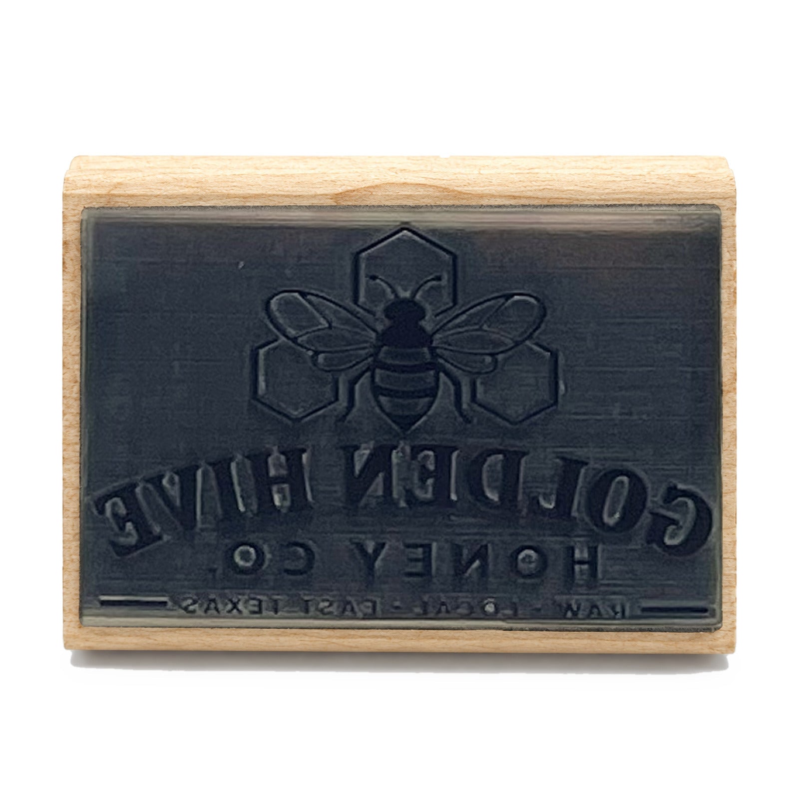 Laser-engraved rubber die face of a custom logo stamp on a maple block