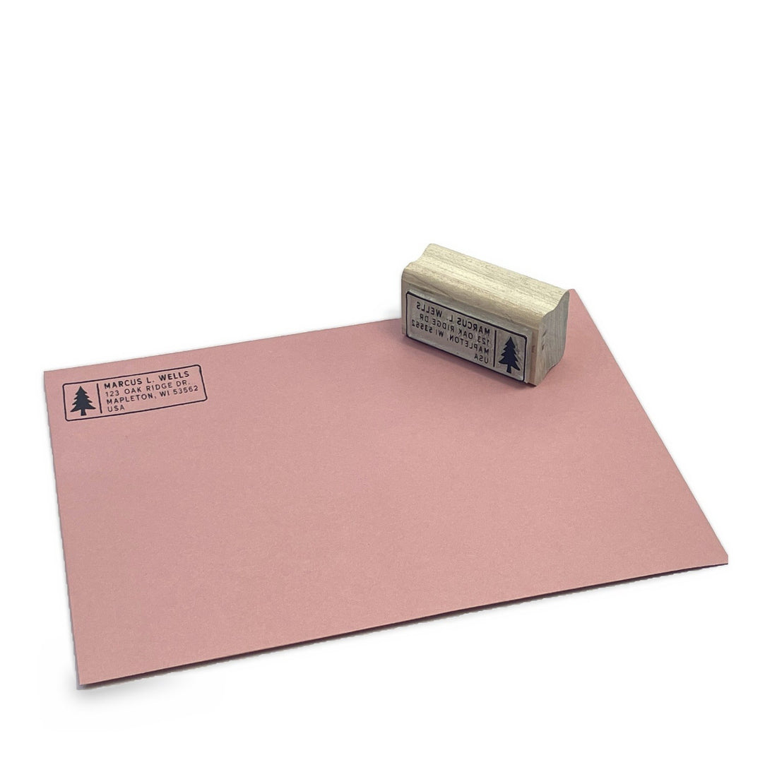 Return address stamp beside a stamped pink envelope