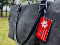 Gray bag with a red medical ID tag on a grassy background