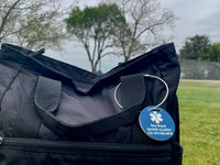Black bag with a blue medical alert tag on a grassy field